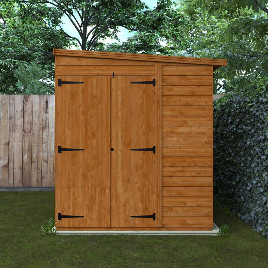 brown wooden shed with black hardware on grass next to a fence and a hedge. 